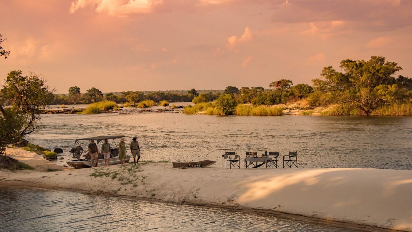Sunset on African River with guests enjoying a wildlife experience and drinks
