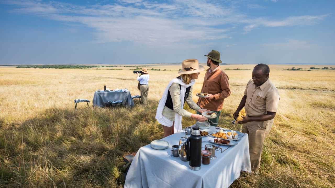 Luxury lunch setting in the African bush with set table for lunch in the open Savanah for a private party of 3 guests