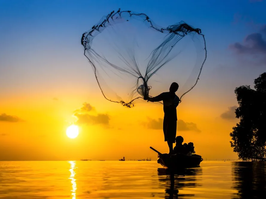 Fisherman throwing a net at sunset on Entebbe Lake, Uganda.