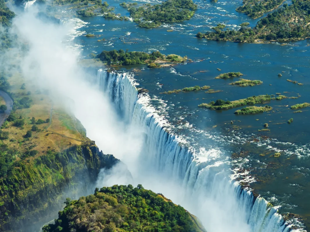 View of Victoria Falls from Zambezi side. It's an aerial shot. Water in full flood, smoke from water with lush green summer light.