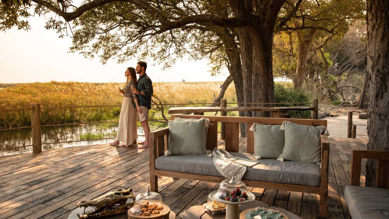Romantic couple on a wooden deck looking out onto the wild African plains on a honeymoon Safari