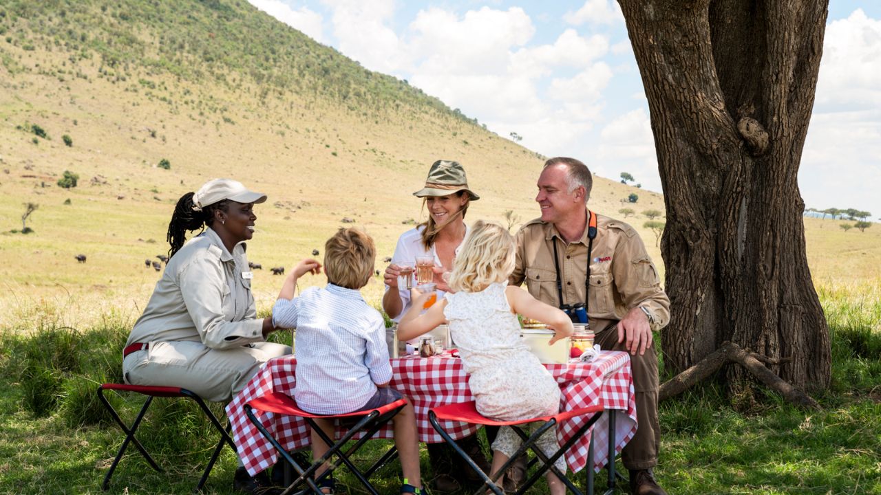 Family on safari having a lunch break with a guide in the Kenyan bush.