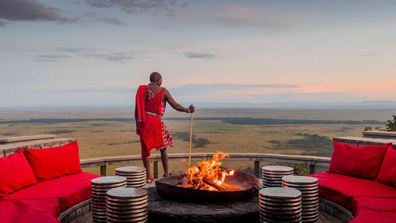 Traditional Kenyan tribesman overlooking Maasai Mara from firepit deck at Angama Mara Safari Camp, Kenya.
