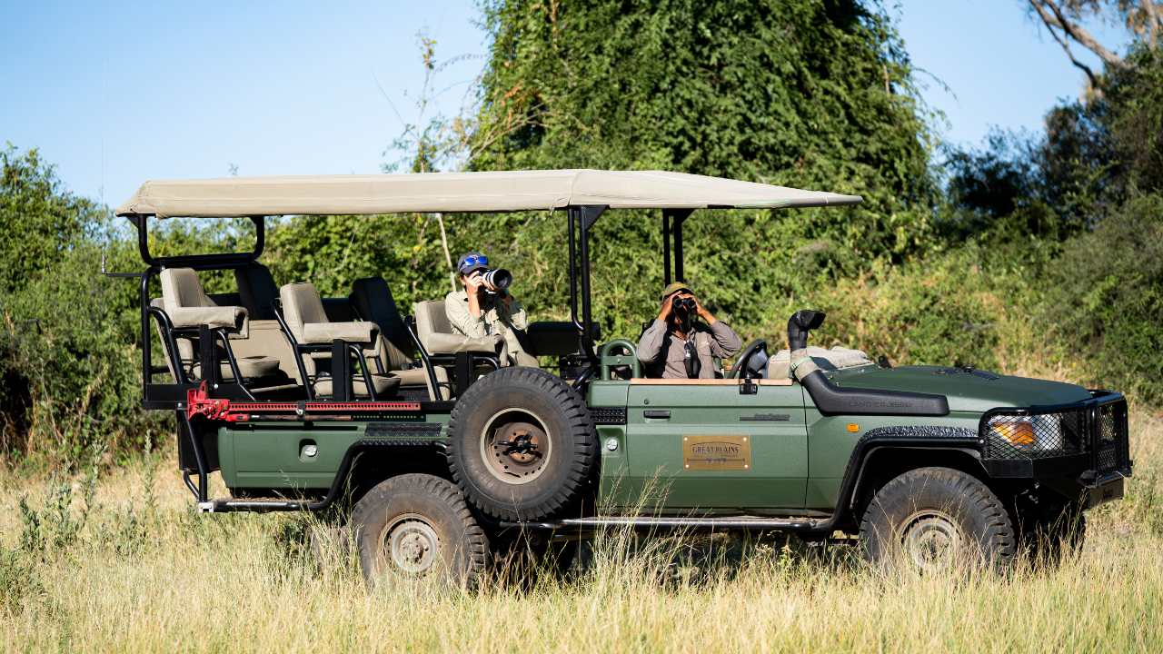 Guide takes a wildlife photographer out on a safari vehicle in the Okavango Delta at Duba Explorers Camp, Botswana.