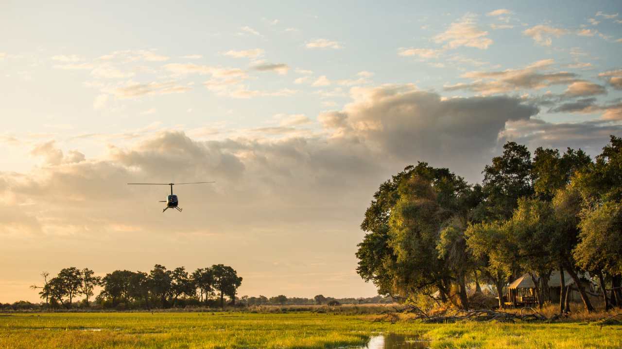 Helicopter flying off for a safari transfer over the main lodge in Botswana’s Okavango Delta.