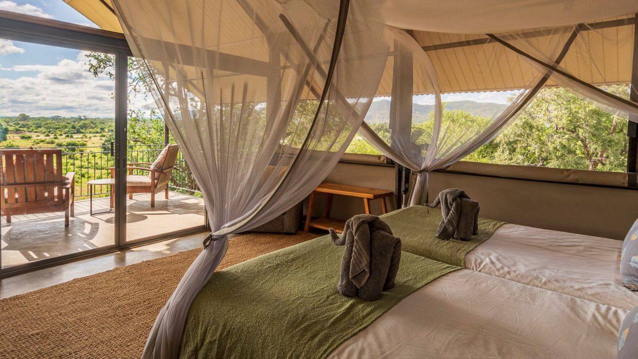 Beds in guest suite at Kavinga Safari Camp looking out onto deck over the wild bush, Zimbabwe.