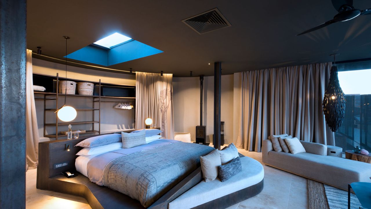Guest suite at Sossusvlei Desert Lodge with double bed, modern lighting and decor