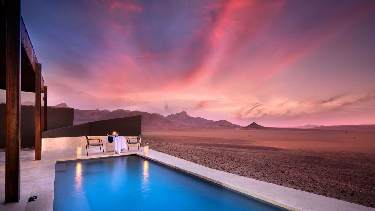 Swimming pool with pink and blue skies at sunset over desert at Sossusvlei Desert Lodge