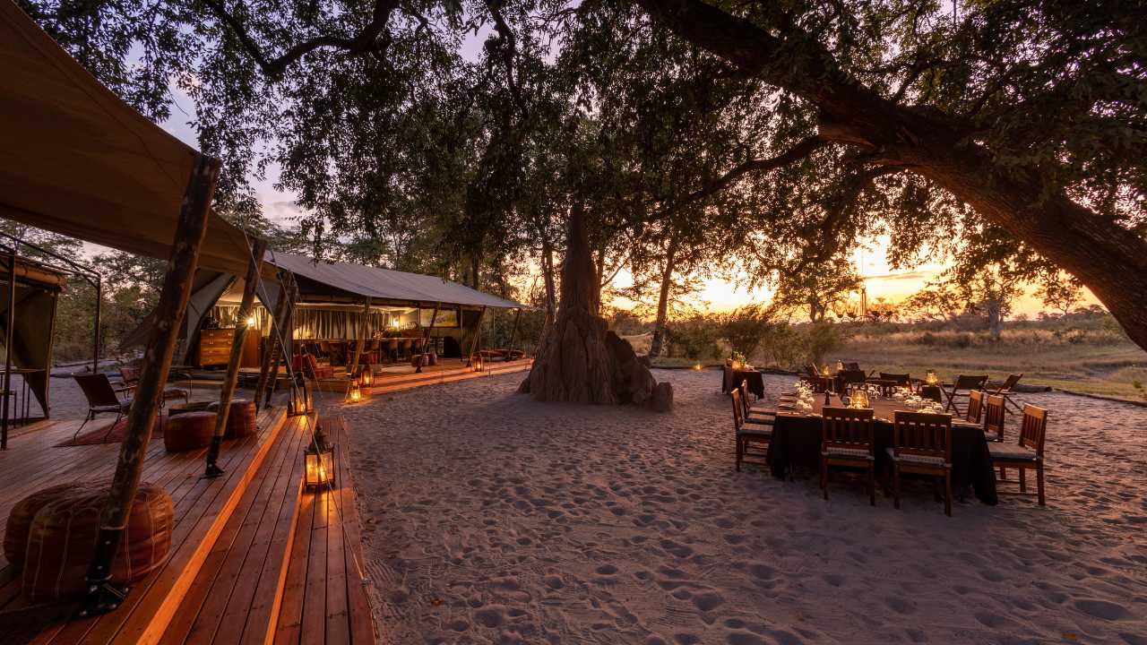 Selinda Explorer Camp main lodge deck at sunset with dining tables.