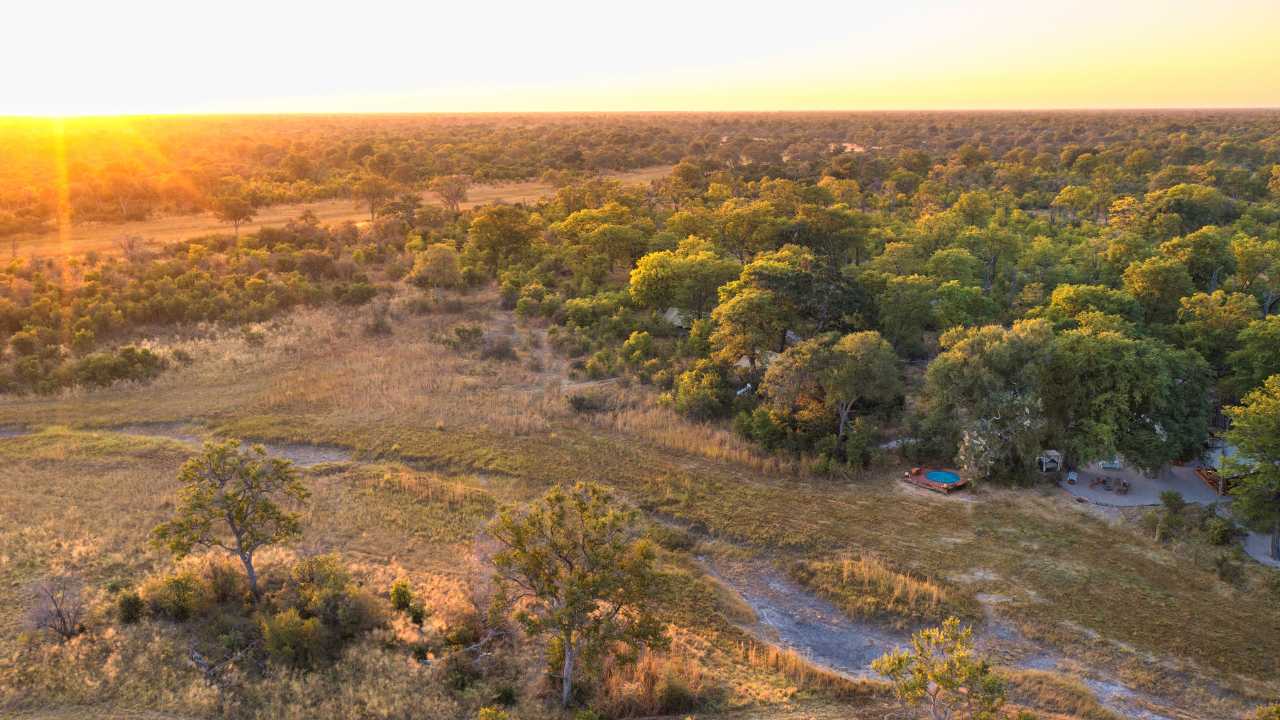 Aerial view of Selinda Camp in Botswana at sunrise, surrounded by bush and waterways.