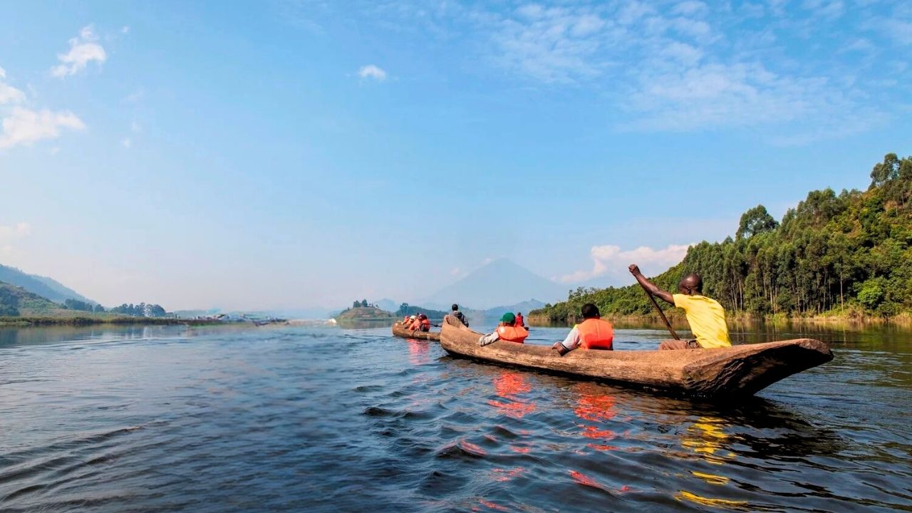 Guide paddling traditional dugout canoe with guests on Lake Mutanda