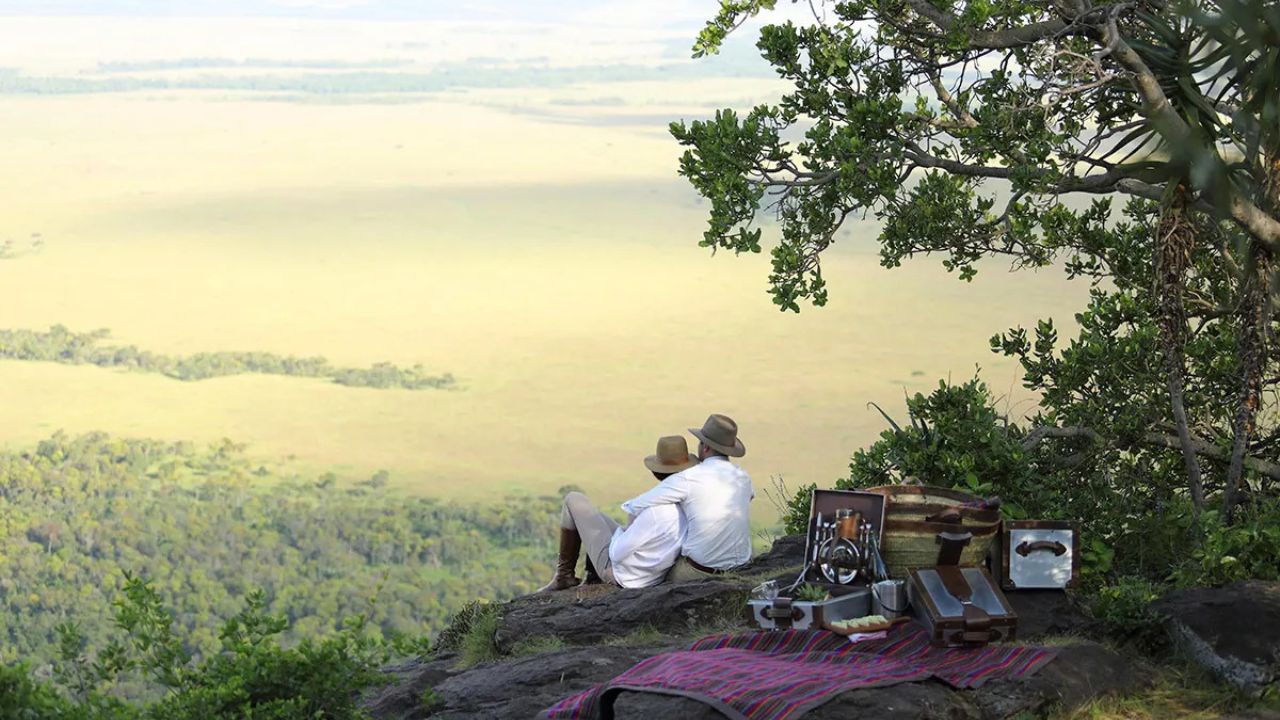 Romantic couple sitting on a rock outcrop overlooking the Maasai Plains in Kenya.