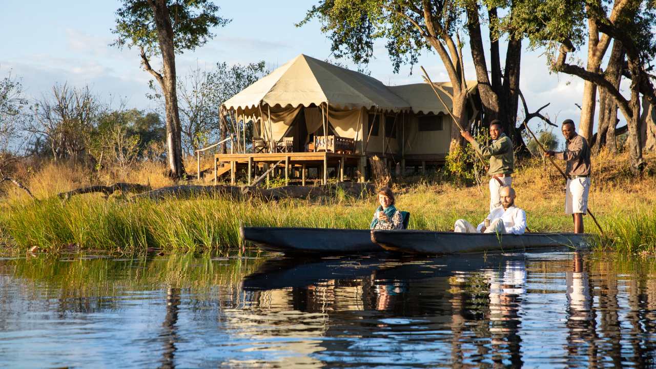 Two safari guides canoeing with guests near Duba Explorers Camp in Botswana’s Okavango Delta.