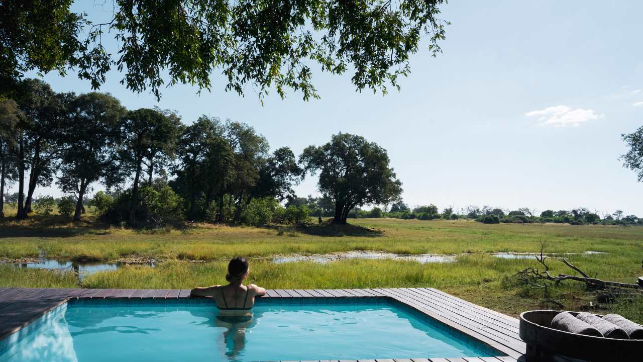 Guests relaxing in the infinity pool at Duba Explorers Camp overlooking Botswana’s Okavango Delta.