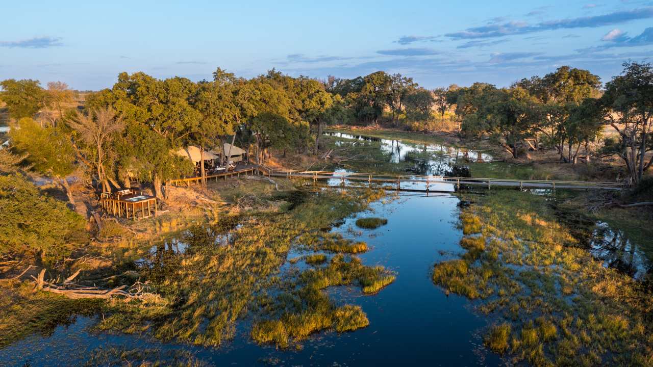 Aerial view of Duba Explorers Camp in Botswana’s Okavango Delta with the lodge on the left and waterways on the right.