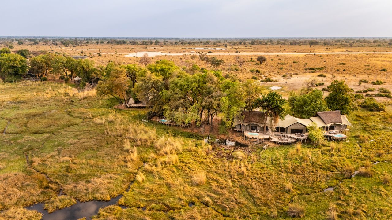 Aerial view of Duba Plains Camp with Okavango Delta in foreground, lodge in center, and dry plains in background, Botswana.