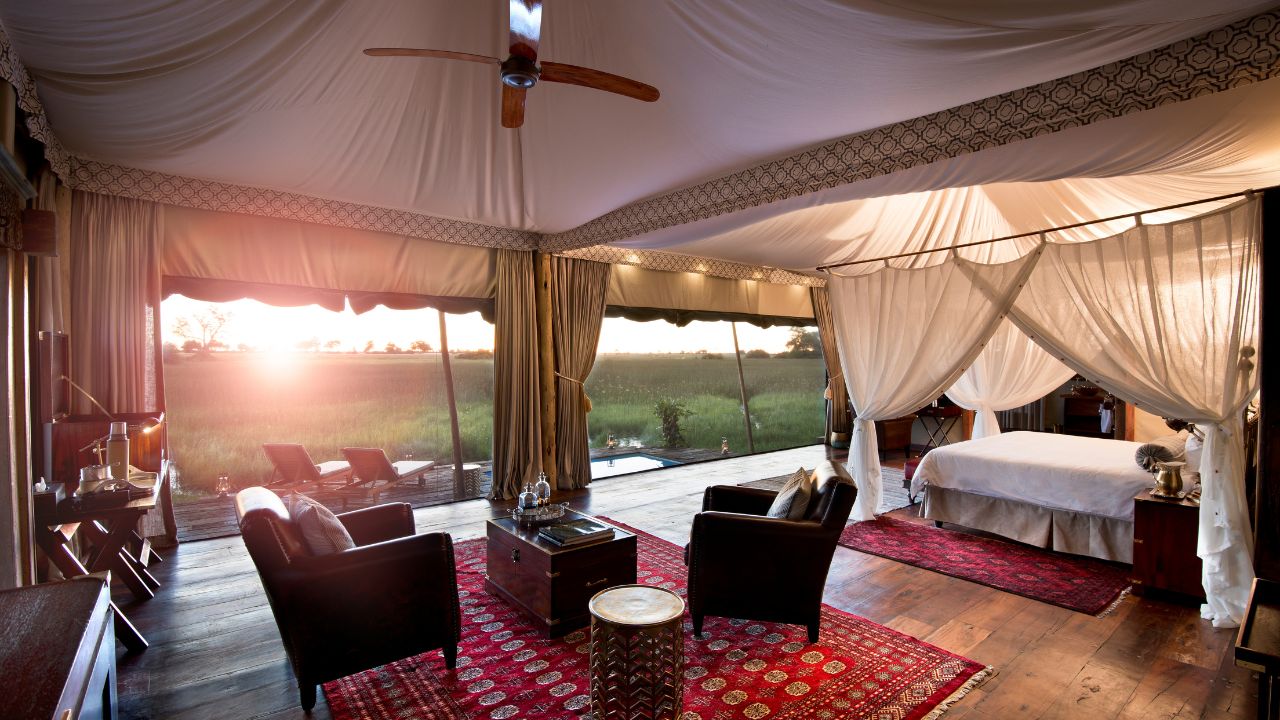 Private lounge area in luxury tented accommodation at Duba Plains Camp with open doors and sunset over Okavango Delta, Botswana.
