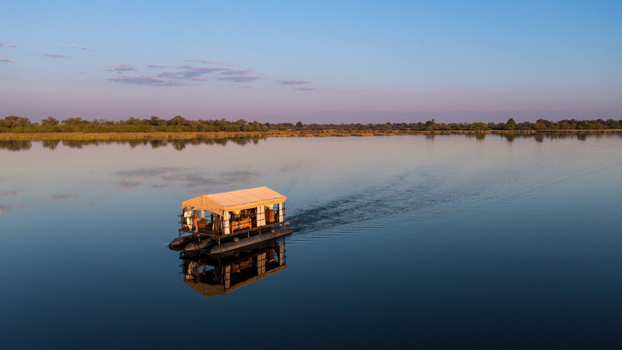 Safari boats on still waters at sunset, Okavango Delta, Zarafa Camp