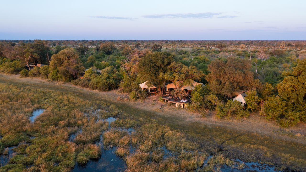 Aerial view of Zarafa Camp from behind with water plains and floodplains of the Okavango Delta, Botswana.