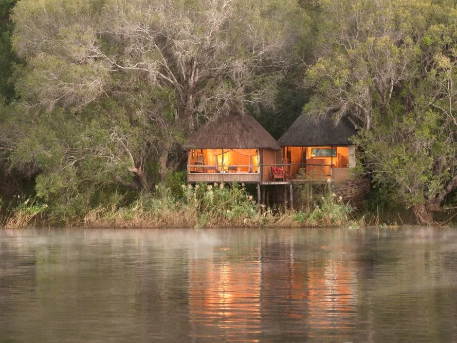 Chundukwa Lodge view from across the river, lodge with lights on in the distance across river in Zambia.