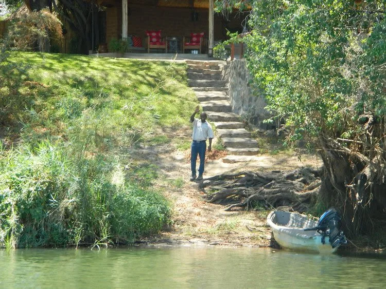 Host at Chundukwa Lodge in Zambia, waving hello from across the river, welcoming guests.
