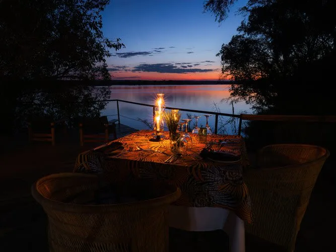 Chundukwa Lodge Zambia dinning table over looking Zambezi river at dusk with candle light on table
