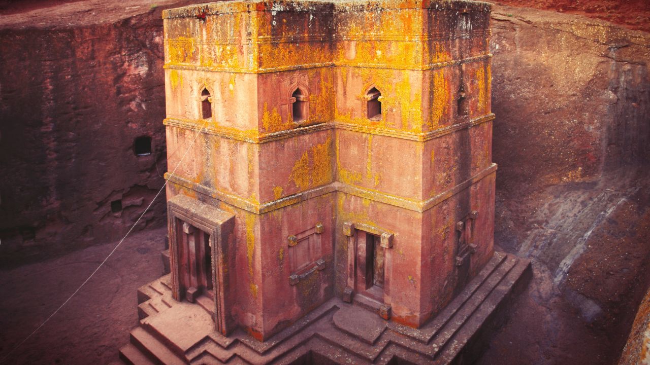 Side view of Lalibela church with pink and yellow walls, no visitors