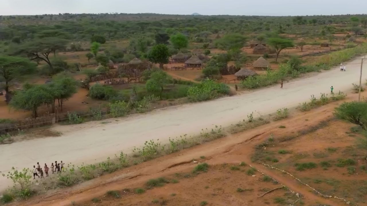 Sand roads leading to Omo Valley tribal village with huts in background.