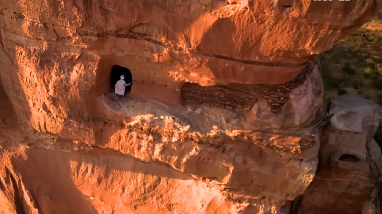 Wide-angle shot of man entering Abuna Yemata Guh monastery through carved rock entrance.