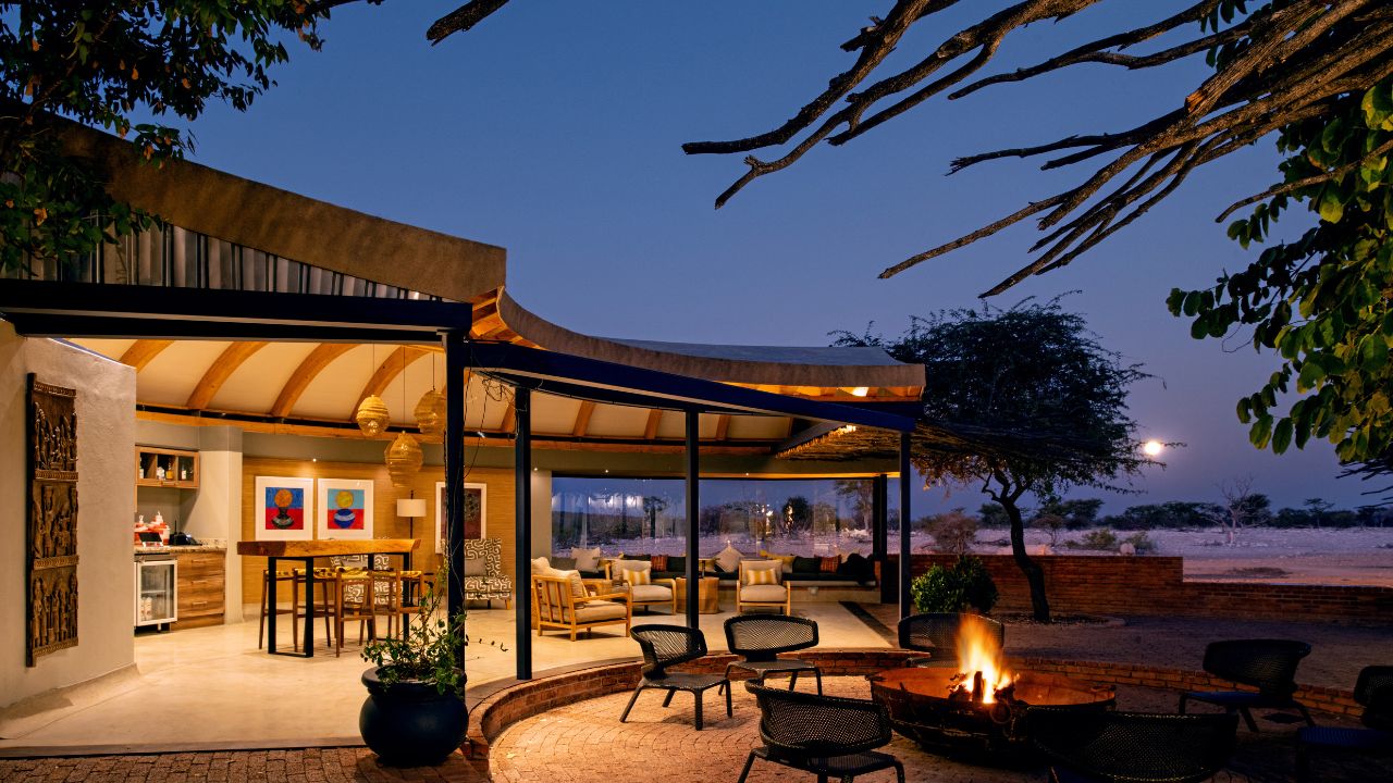 Main lodge at night with boma fire glowing as the sun sets, buildings lit up