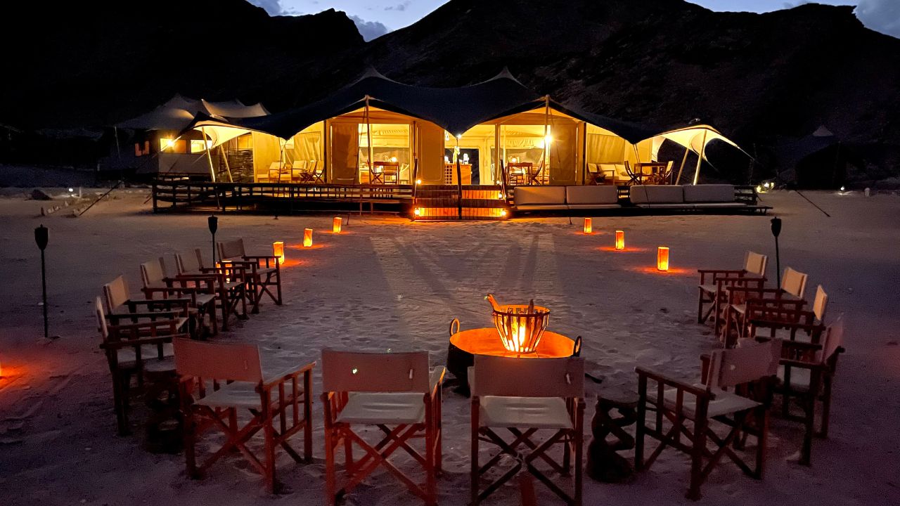 Main lodge illuminated at night with boma campfire and candlelit seating under the desert sky
