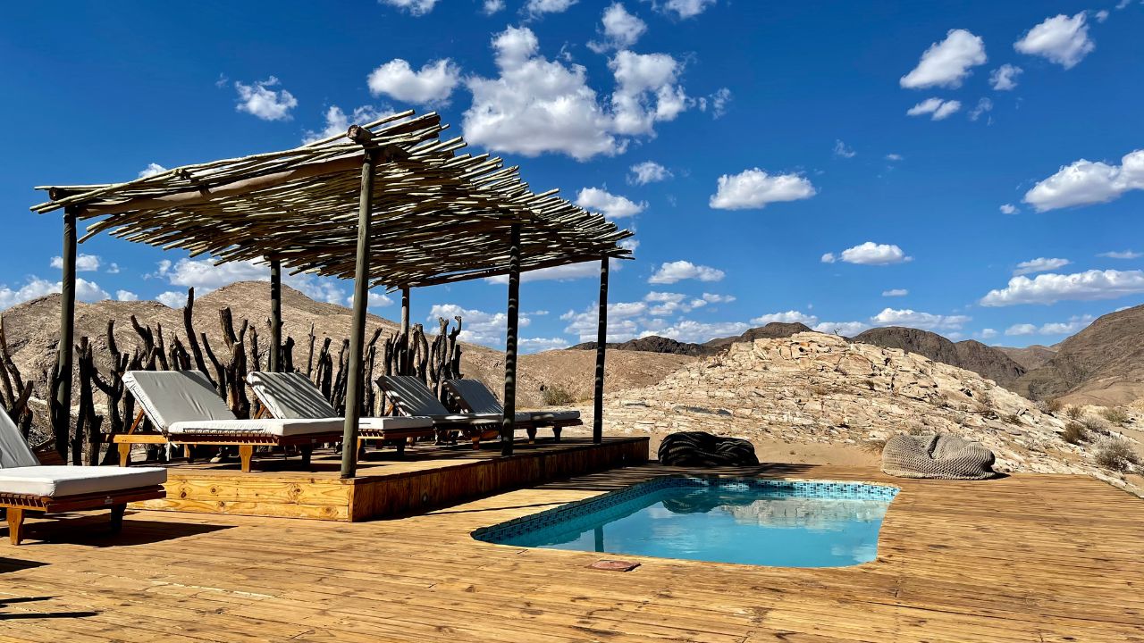 Swimming pool with shaded straw hut surrounded by desert landscape