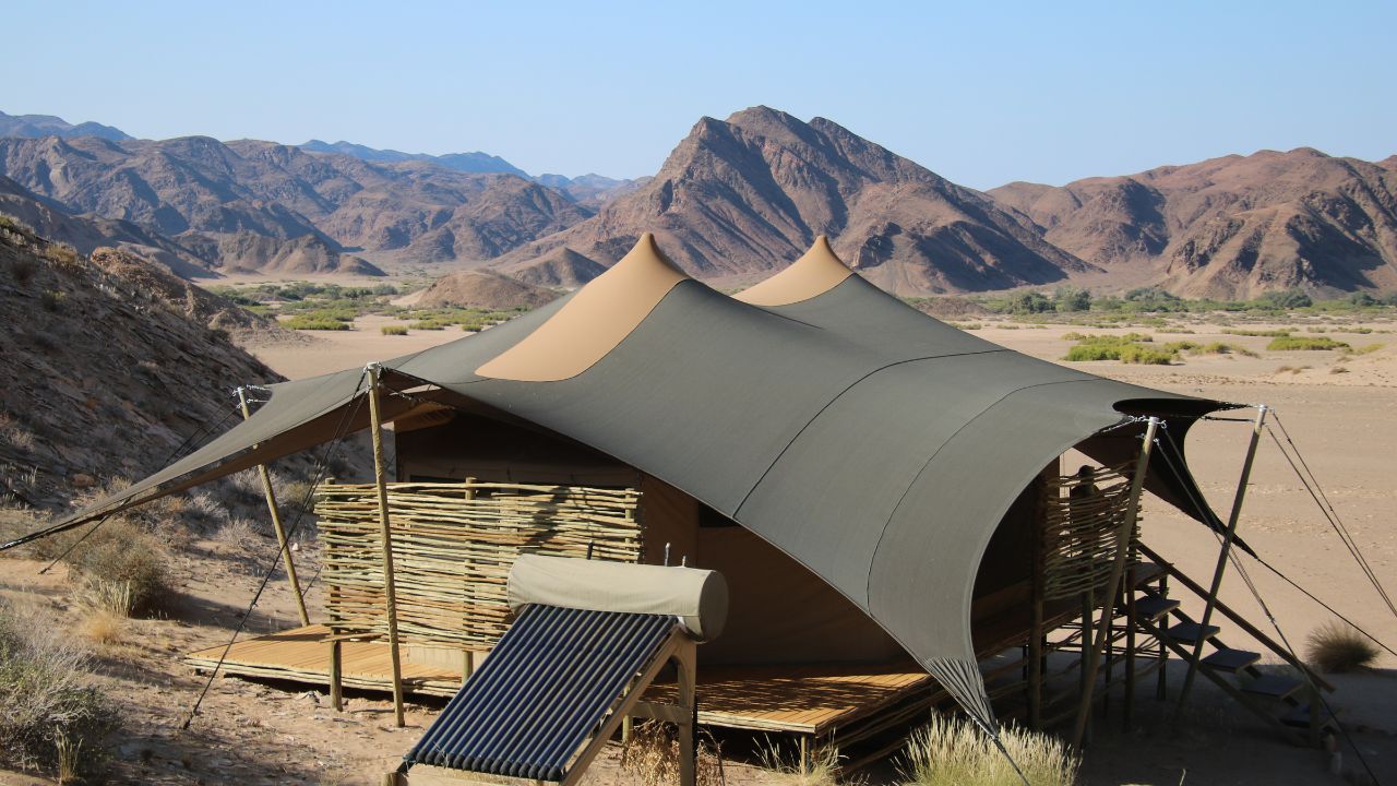Rear view of tented accommodation with solar panel and surrounding desert