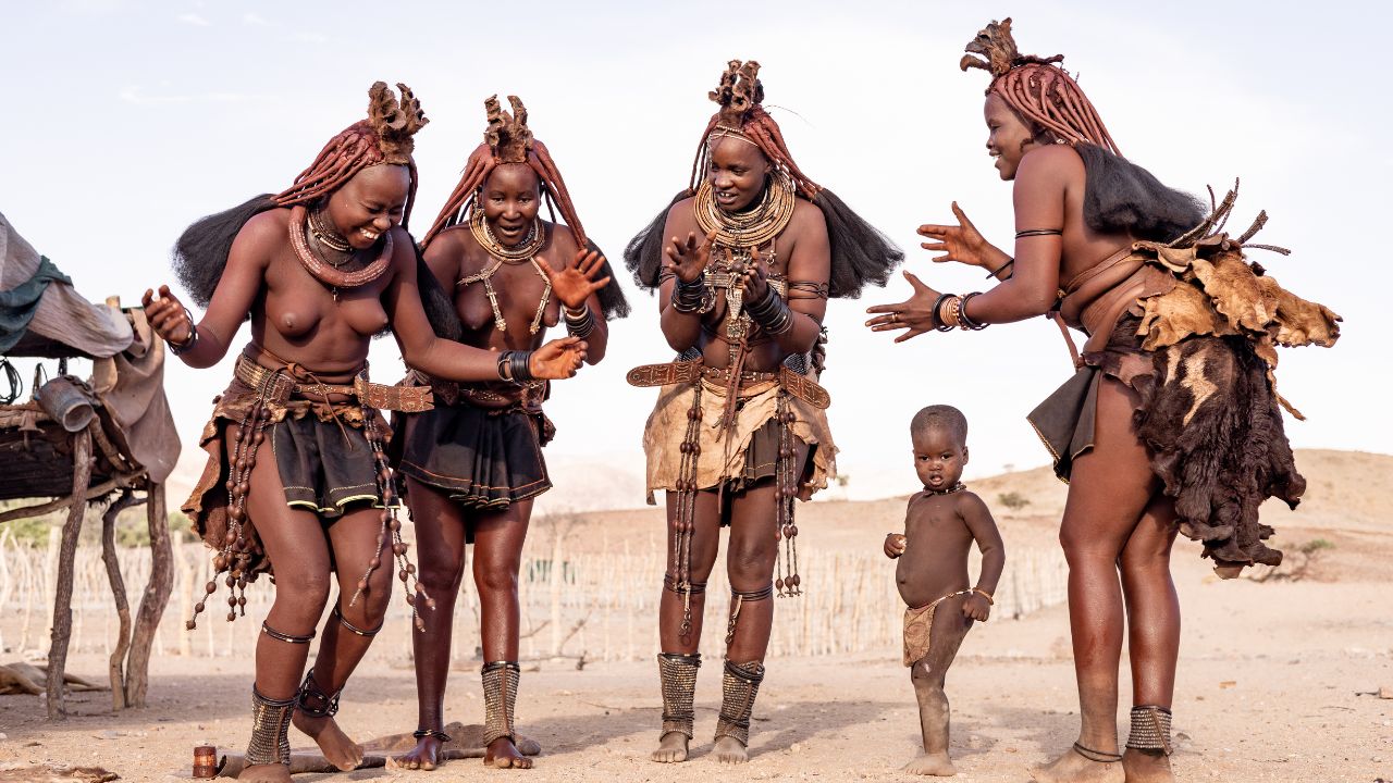Himba women performing traditional tribal dance with infant