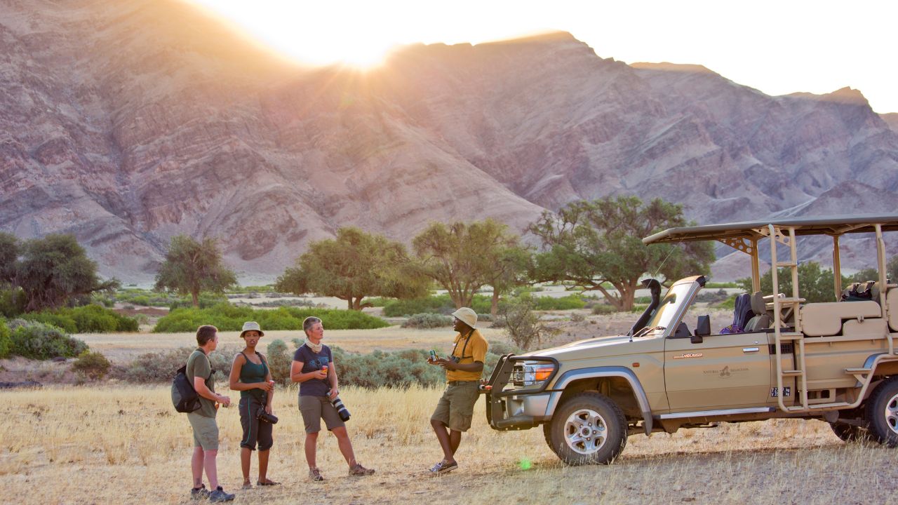 Guests listening to safari guide on walking photography tour at sunrise in the desert
