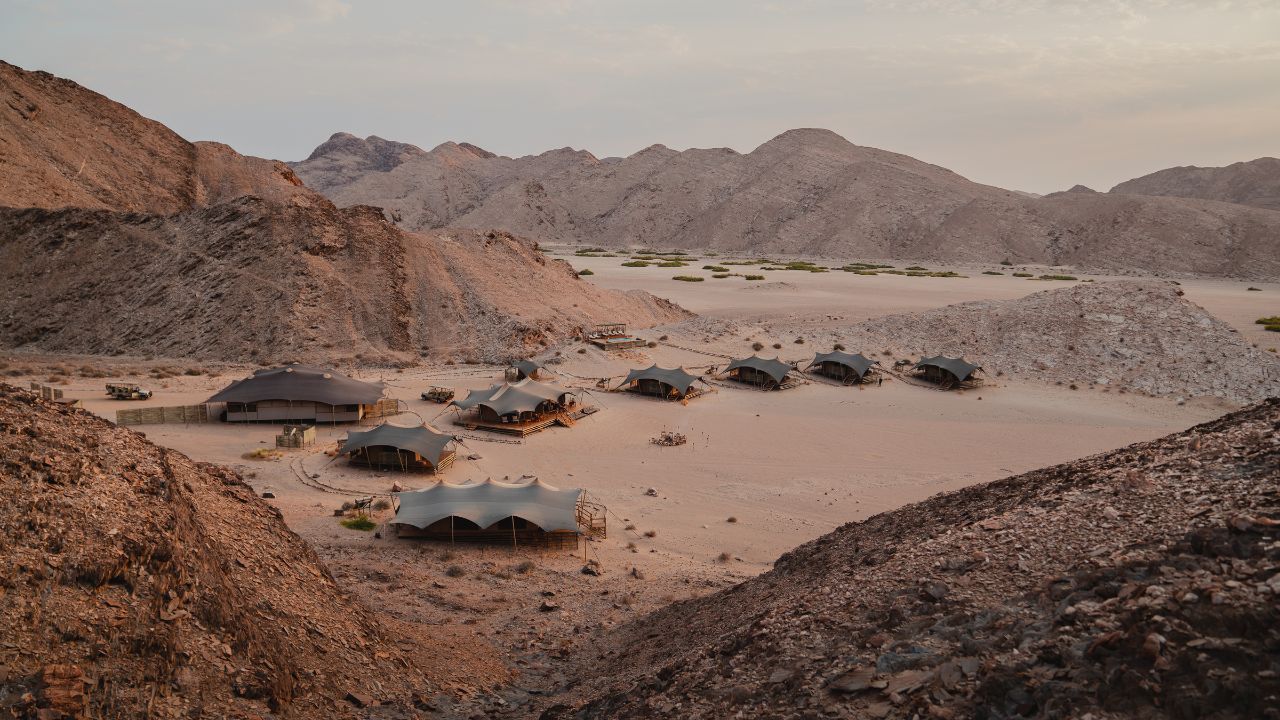 Elevated view of Hoanib Valley Camp nestled among vast sand dunes on a flat desert plain in northwestern Namibia