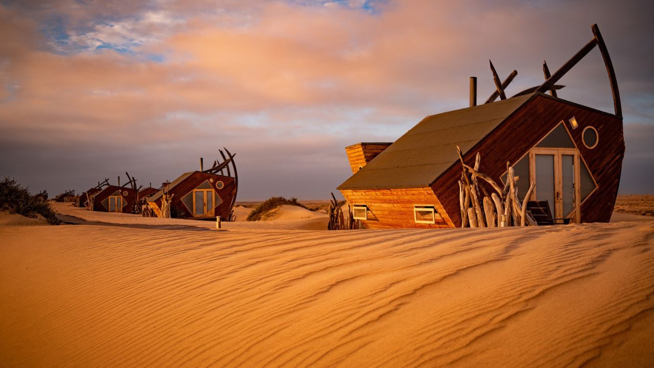 Sunset over Shipwreck Lodge with orange skies and desert dunes
