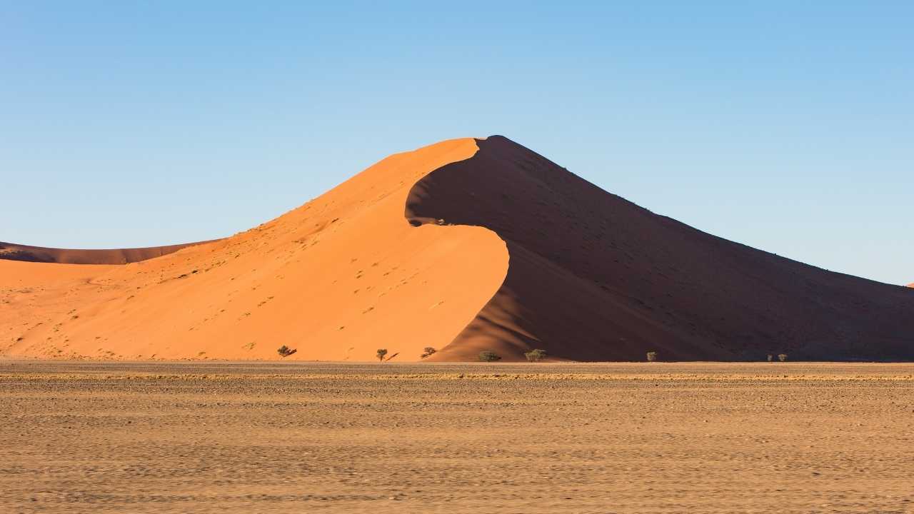 Incredible red sand dunes of Sossusvlei in Namibia under clear skies.