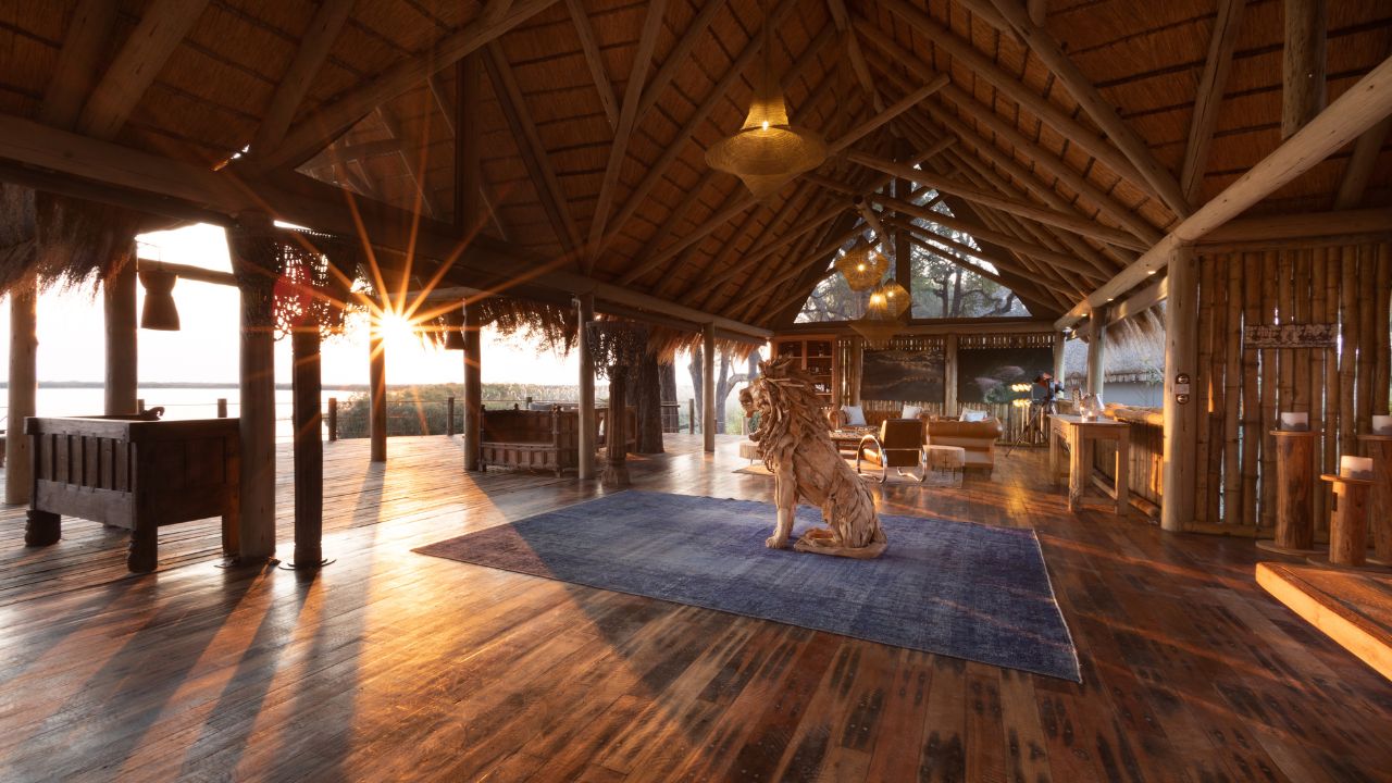 Main lodge and lounge at Sitatunga Private Island with lion sculpture guarding entrance and sunset over the Okavango Delta.