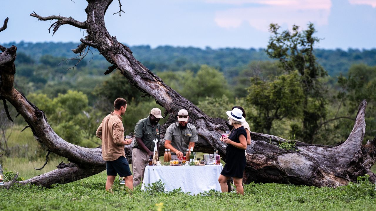 Ranger and tracker preparing romantic sunset drinks table in Kruger bush