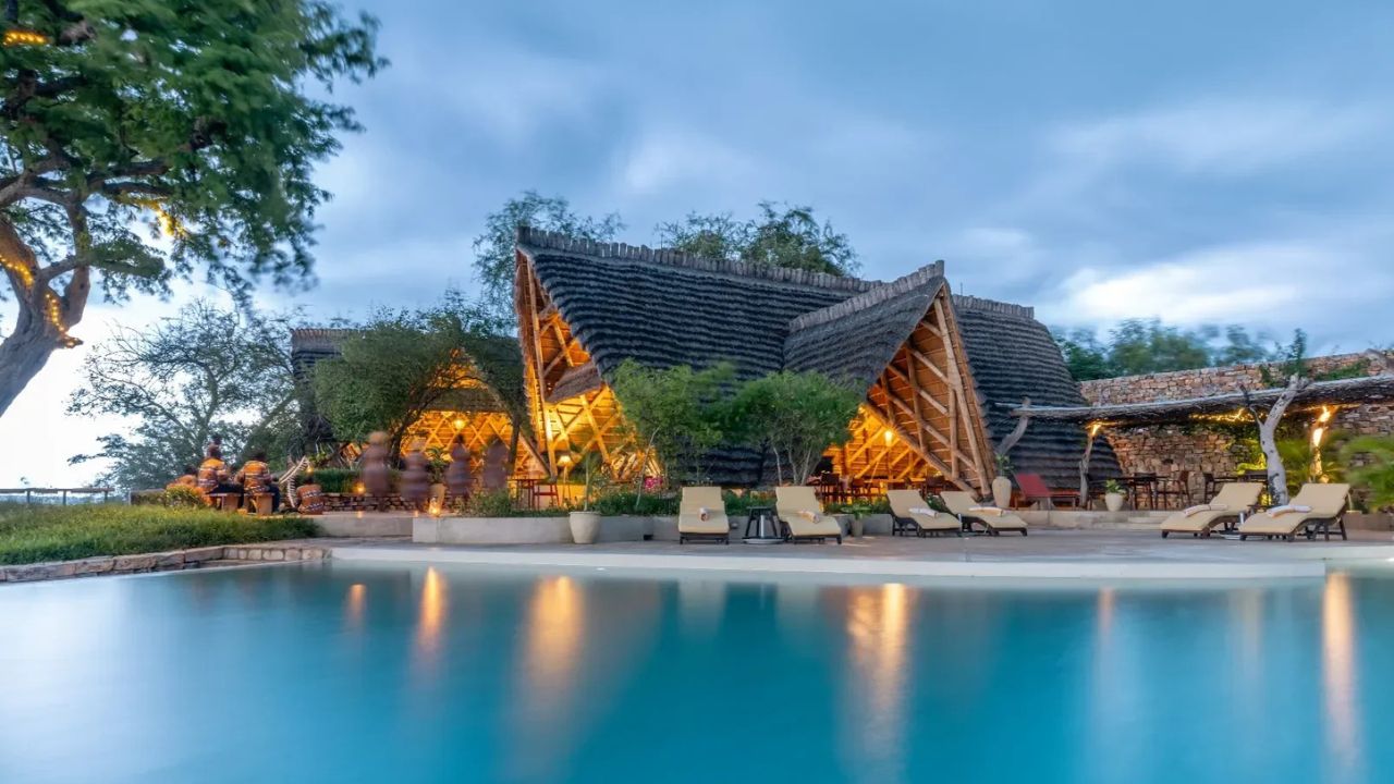 Sunset over pool with thatched lodge and reflections, Nile Safari Lodge Uganda