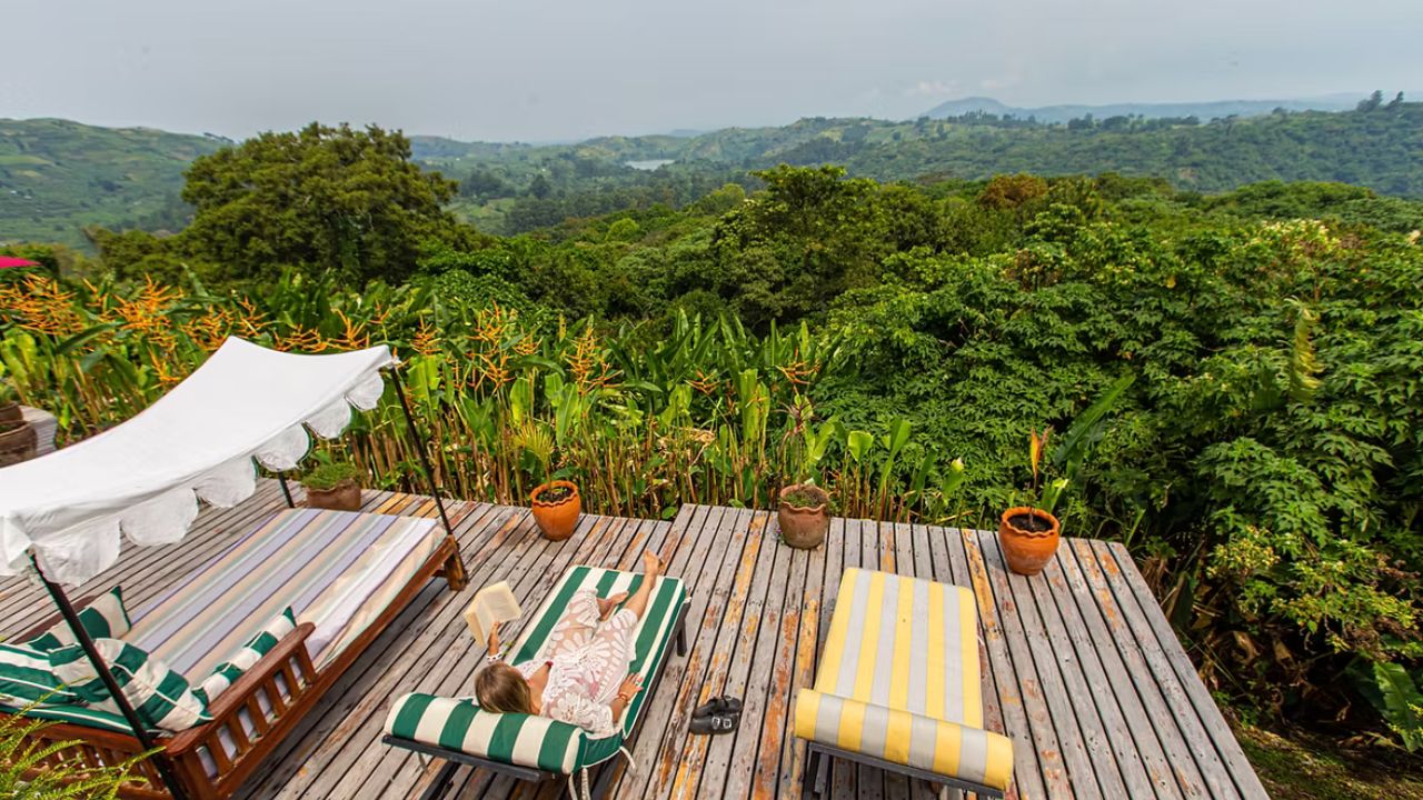 Lounge chairs on wooden deck at Ndali Lodge overlooking lush Ugandan jungle.