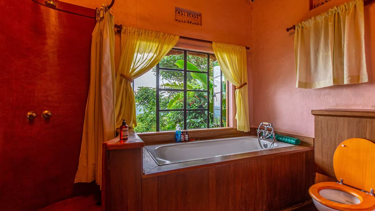 Freestanding bathtub beside large window overlooking jungle at Ndali Lodge.