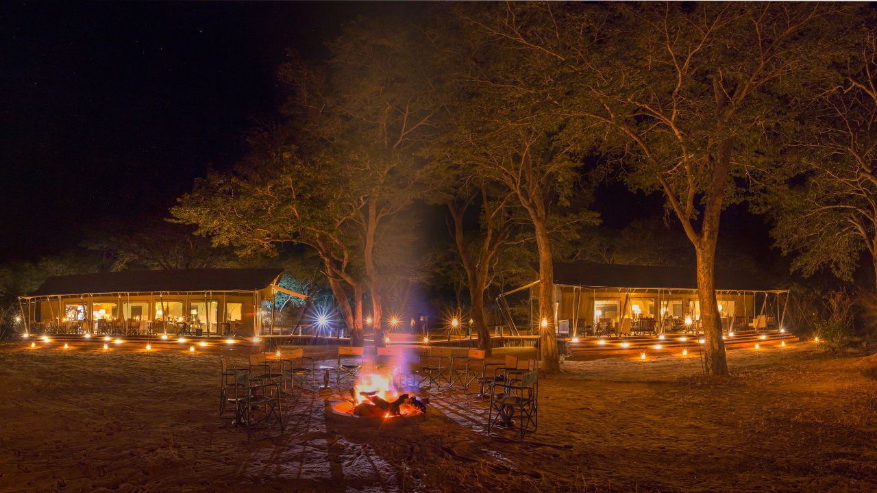 Boma fire burning with main lodge lit up in background, Verny’s Camp