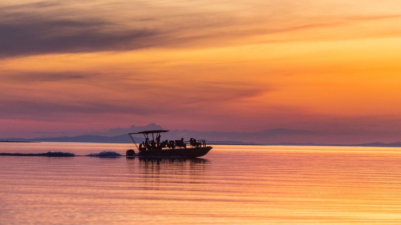 Long-range shot of boat cruising Lake Kariba at sunset, golden light