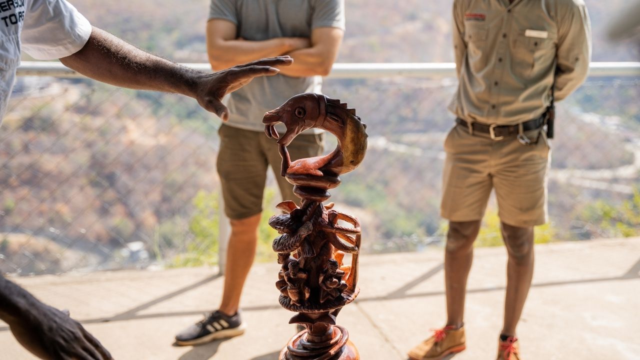 Guide explaining Nyami Nyami statue, god of Lake Kariba, to guests