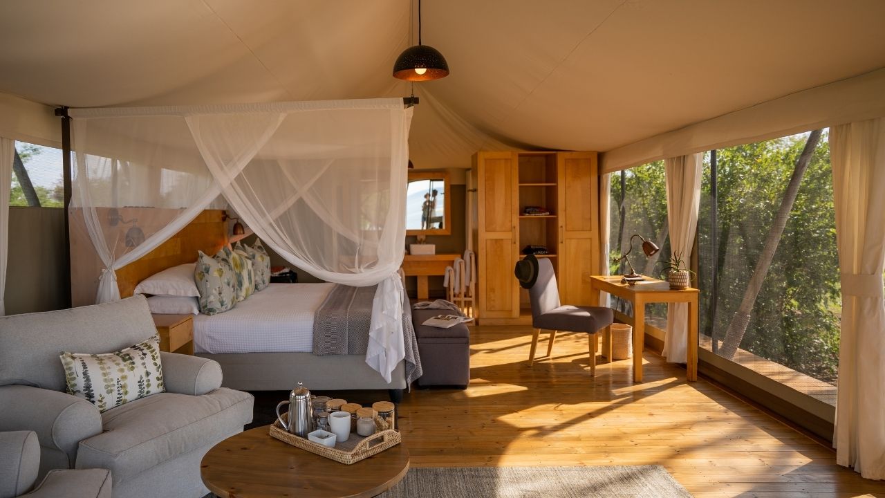 Side view of double bed in suite with sunlight streaming through windows