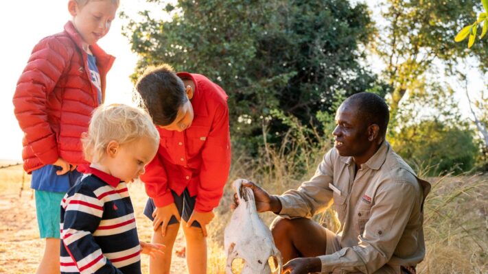Safari guide explaining skeletal remains to three young children, Fothergill Island