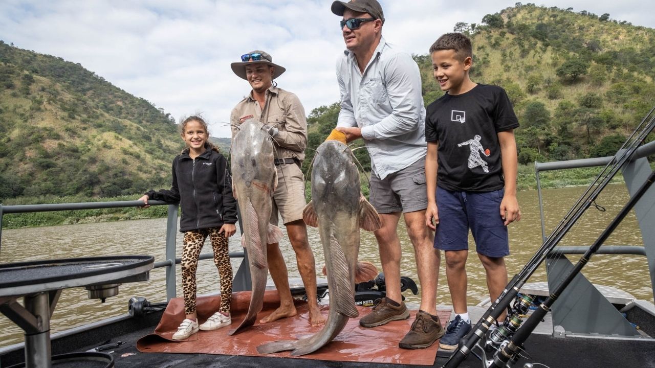 Two fathers showing huge fish catches with kids on Lake Kariba, Zimbabwe