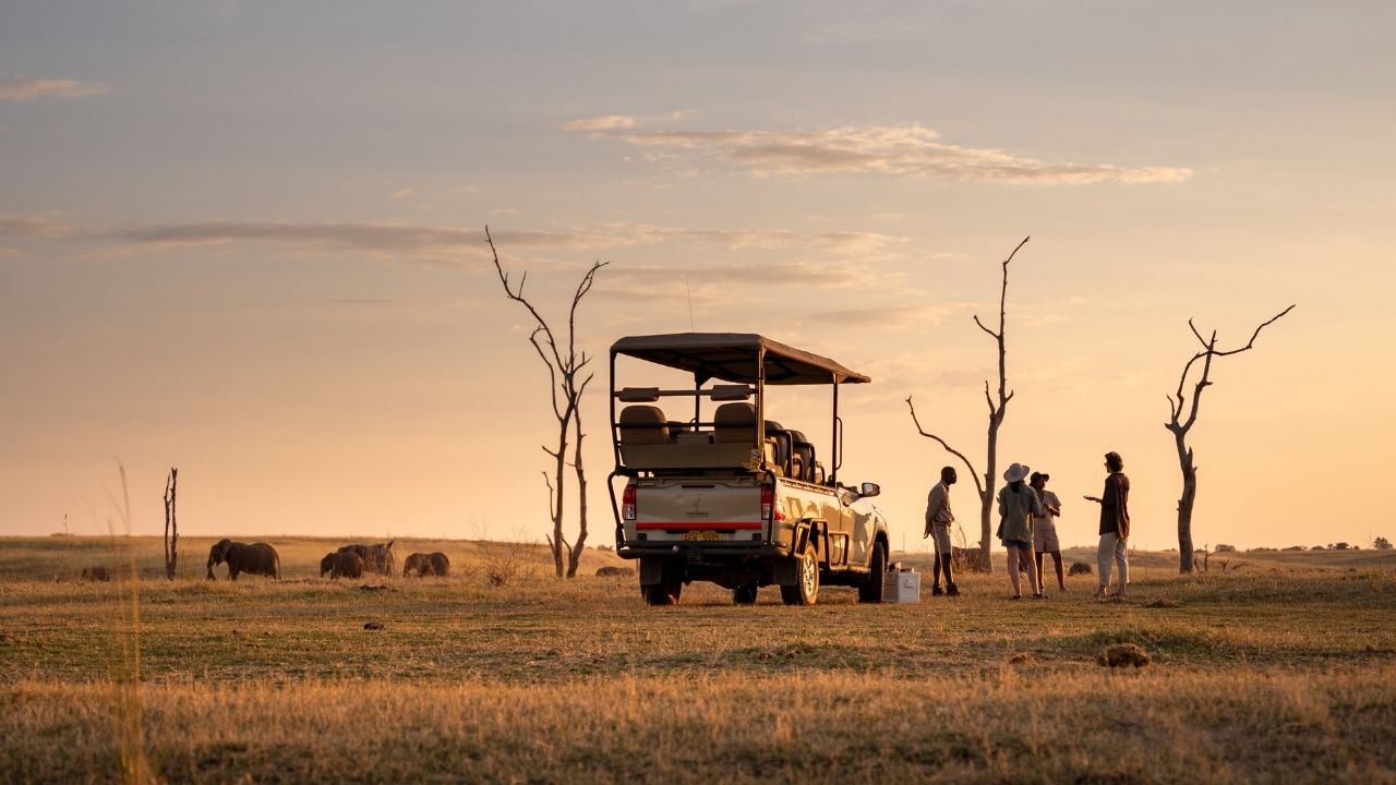 Safari vehicle at sunset with guests stopped for sundowner drinks